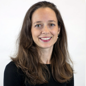Woman with long brown hair smiling in a black top, headshot portrait